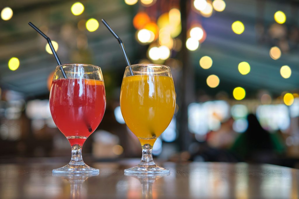 Two glasses with yellow and red tasty sweet beverage on restaurant table